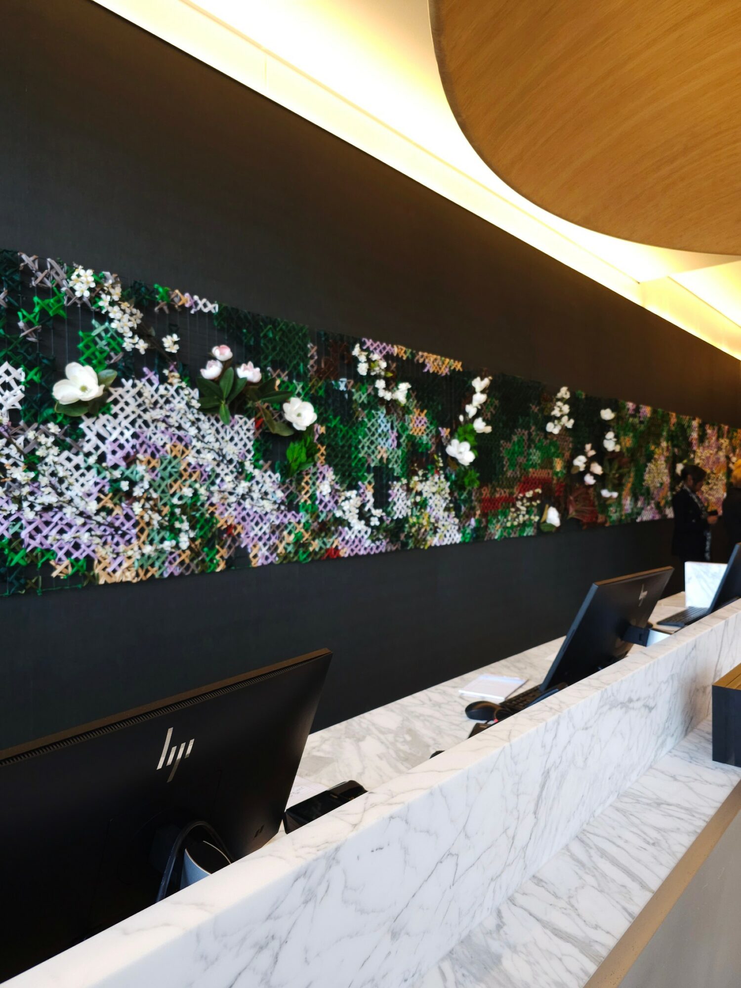 Interior with a black wall decorated with a colorful floral mosaic, white marble counter, and computer monitors.