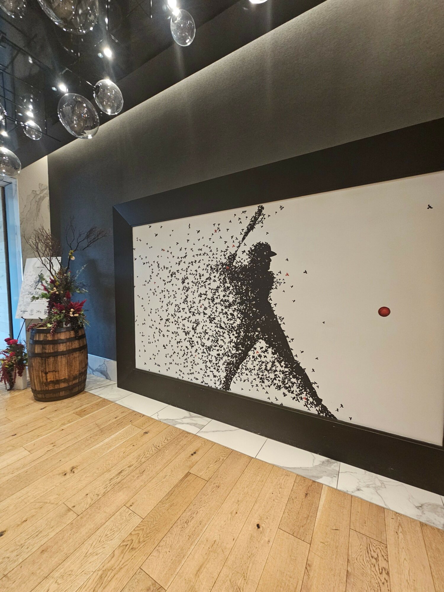 Ceiling with black splatter design, wooden floor, and a barrel with flowers nearby.