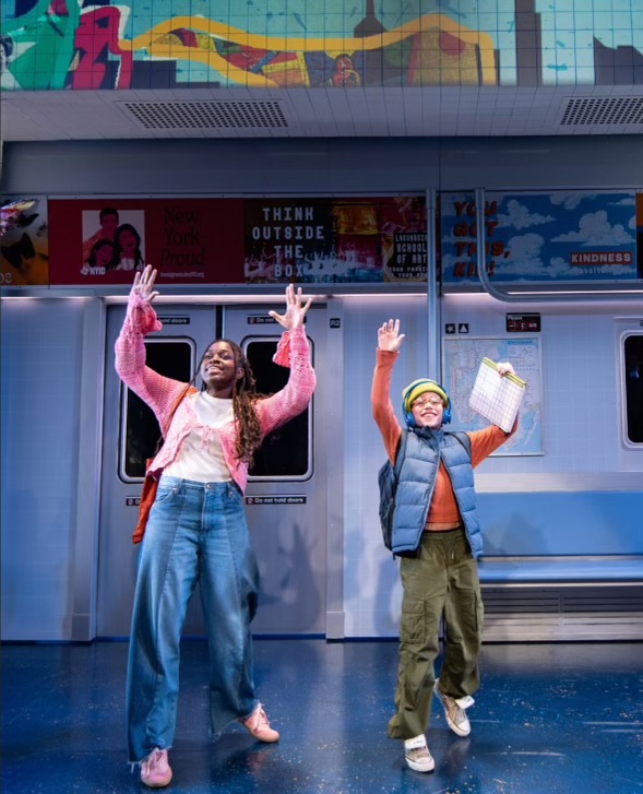 Two people standing on a subway platform, waving and smiling, with colorful graffiti above and a subway train behind them.