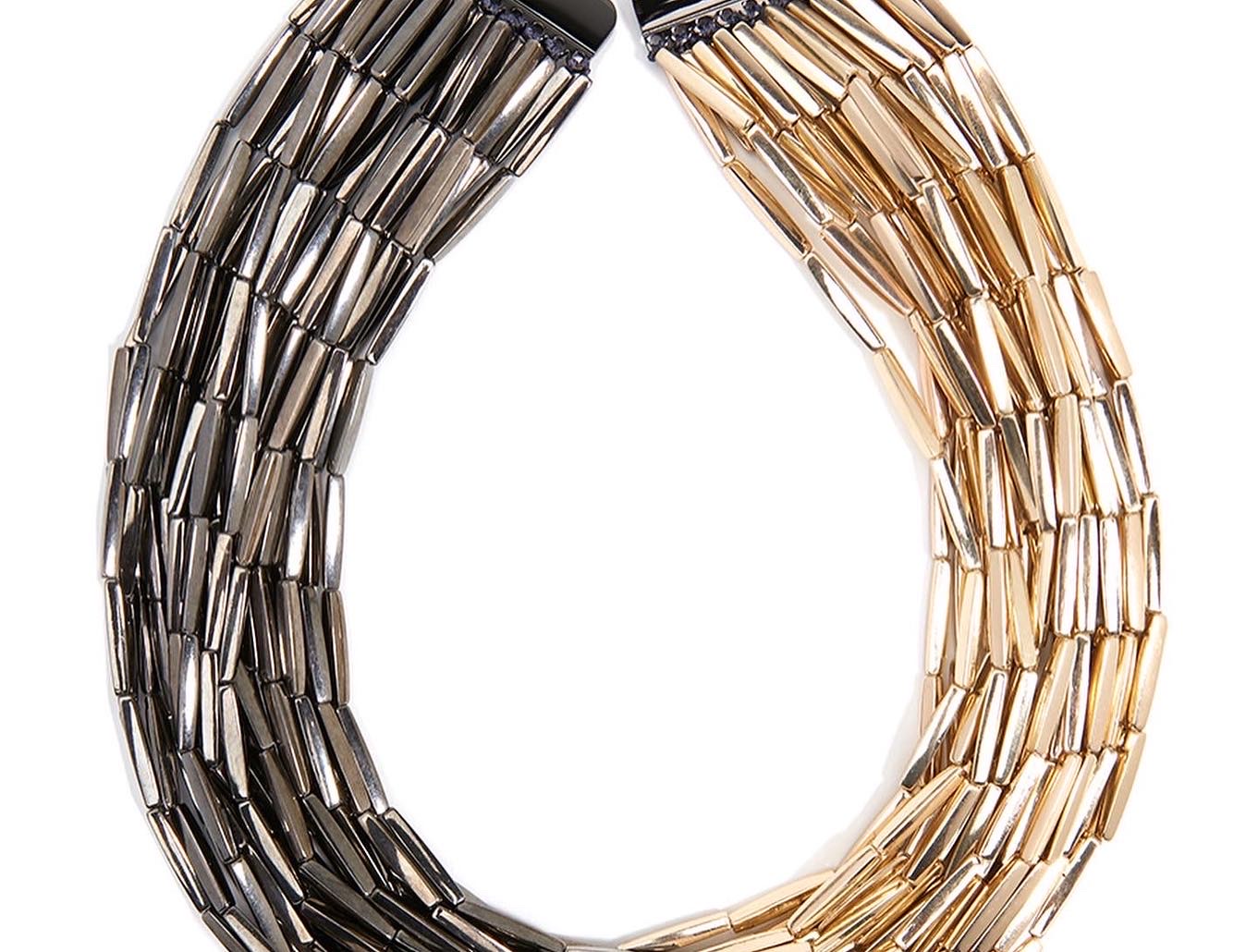 Two curved metallic necklaces, one silver and one gold, arranged in a U-shape against a white background.