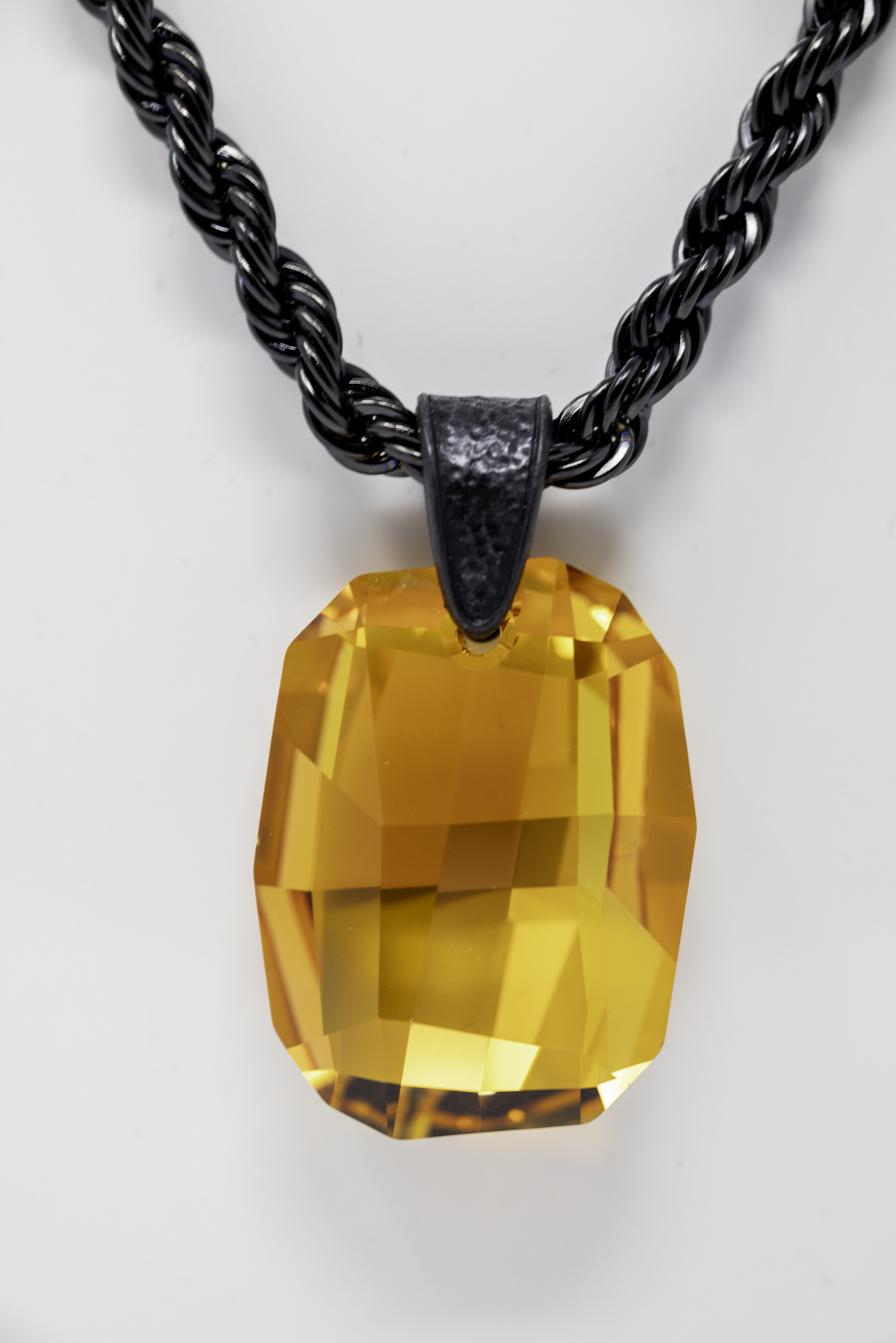 Black twisted chain necklace with large orange gemstone pendant, against a white background.