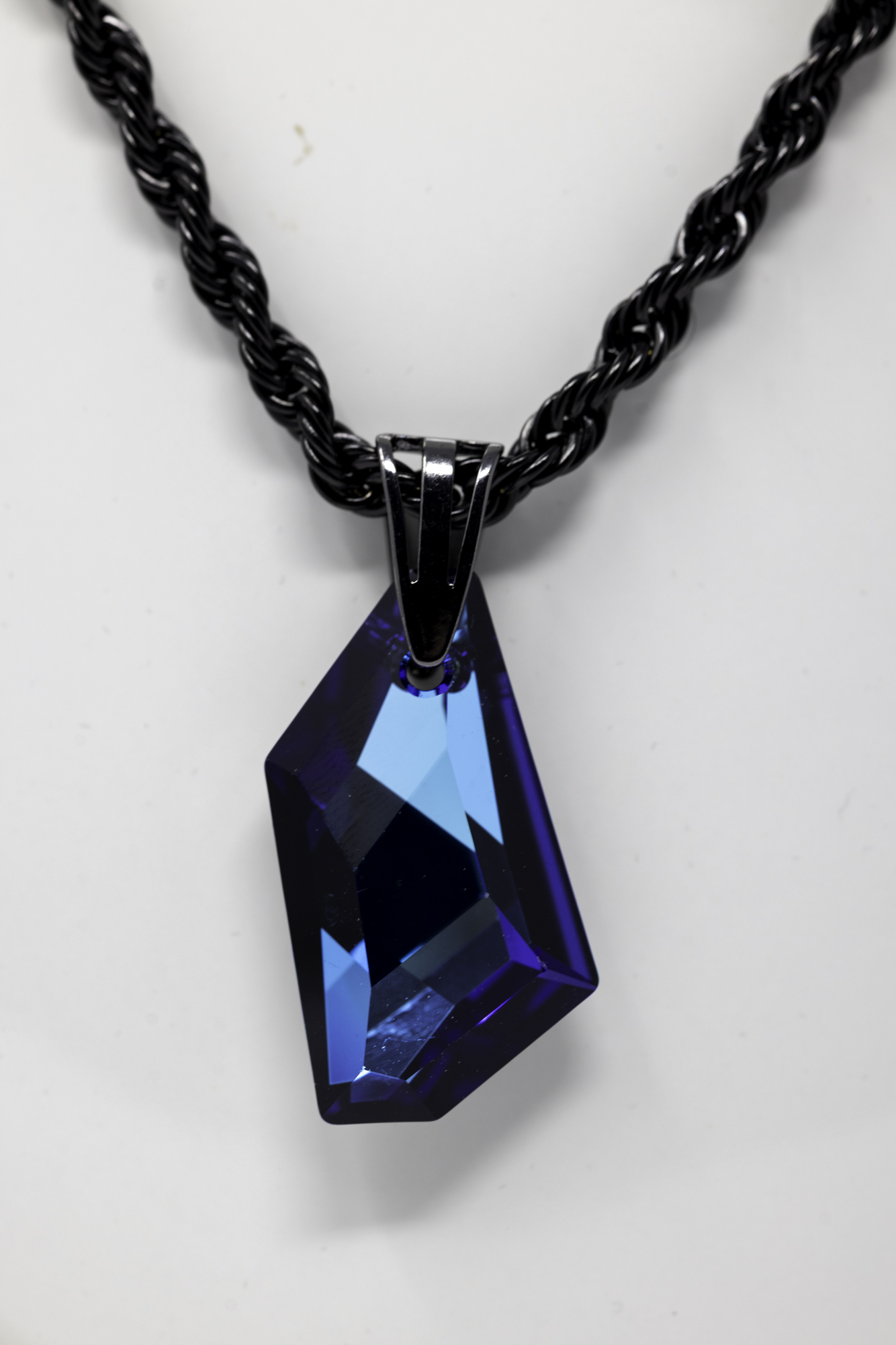 Black twisted chain necklace with a large blue geometric pendant hanging from it.