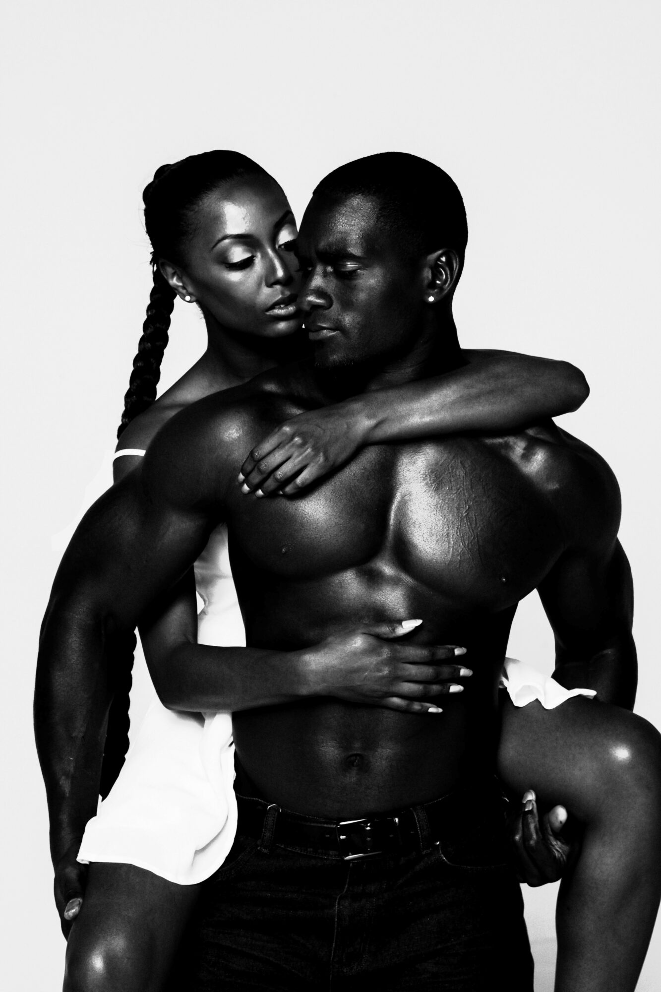 Two people, one with braided hair, embrace closely, with the person in front holding the other around the shoulders.