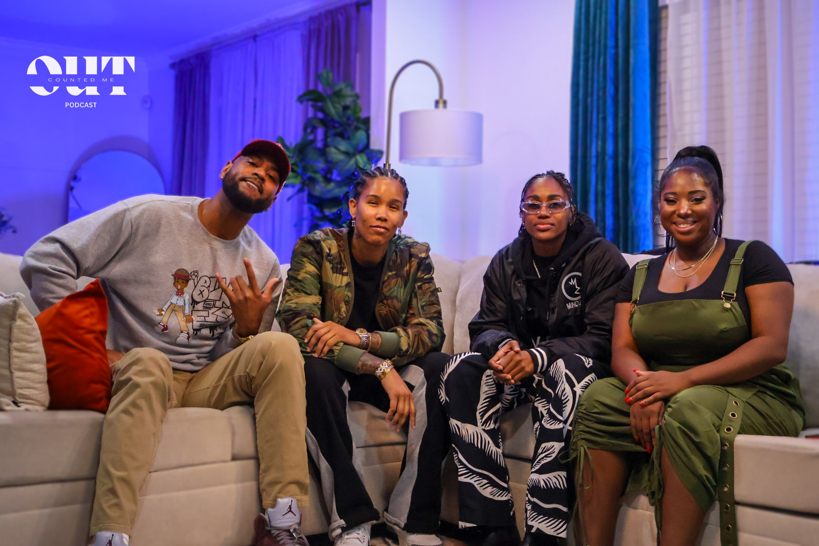 Four people sitting on a sofa in a living room, smiling and posing for the camera.