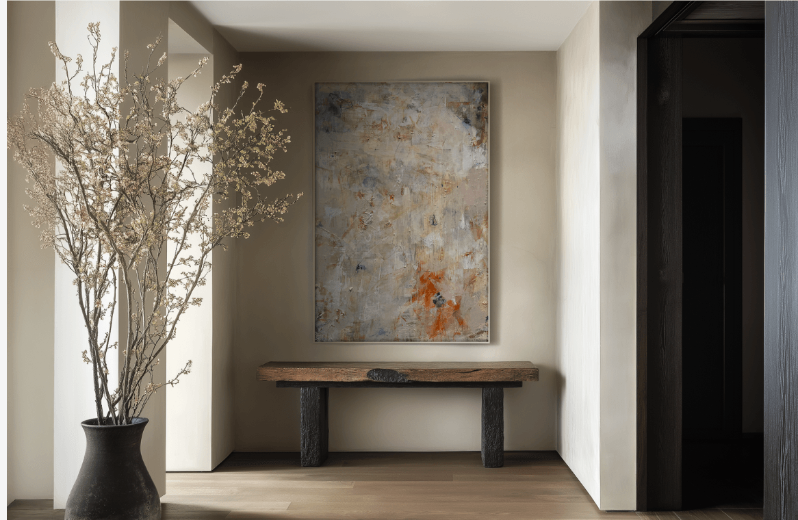 Interior space with a large abstract painting on the wall, a wooden bench below, and a tall vase with branches on the left.
