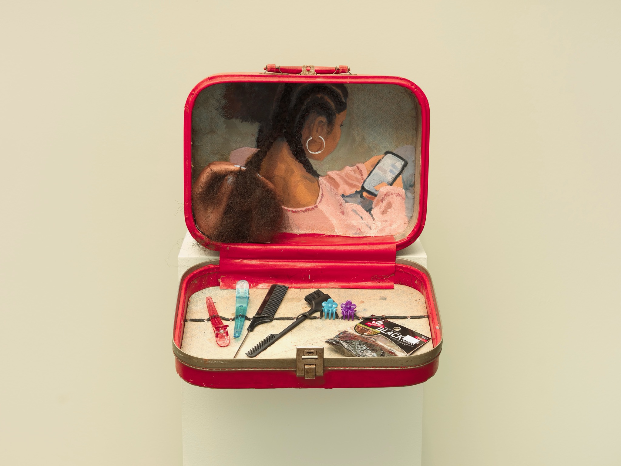 A woman with headphones looks at her phone inside a red case with makeup items and accessories.