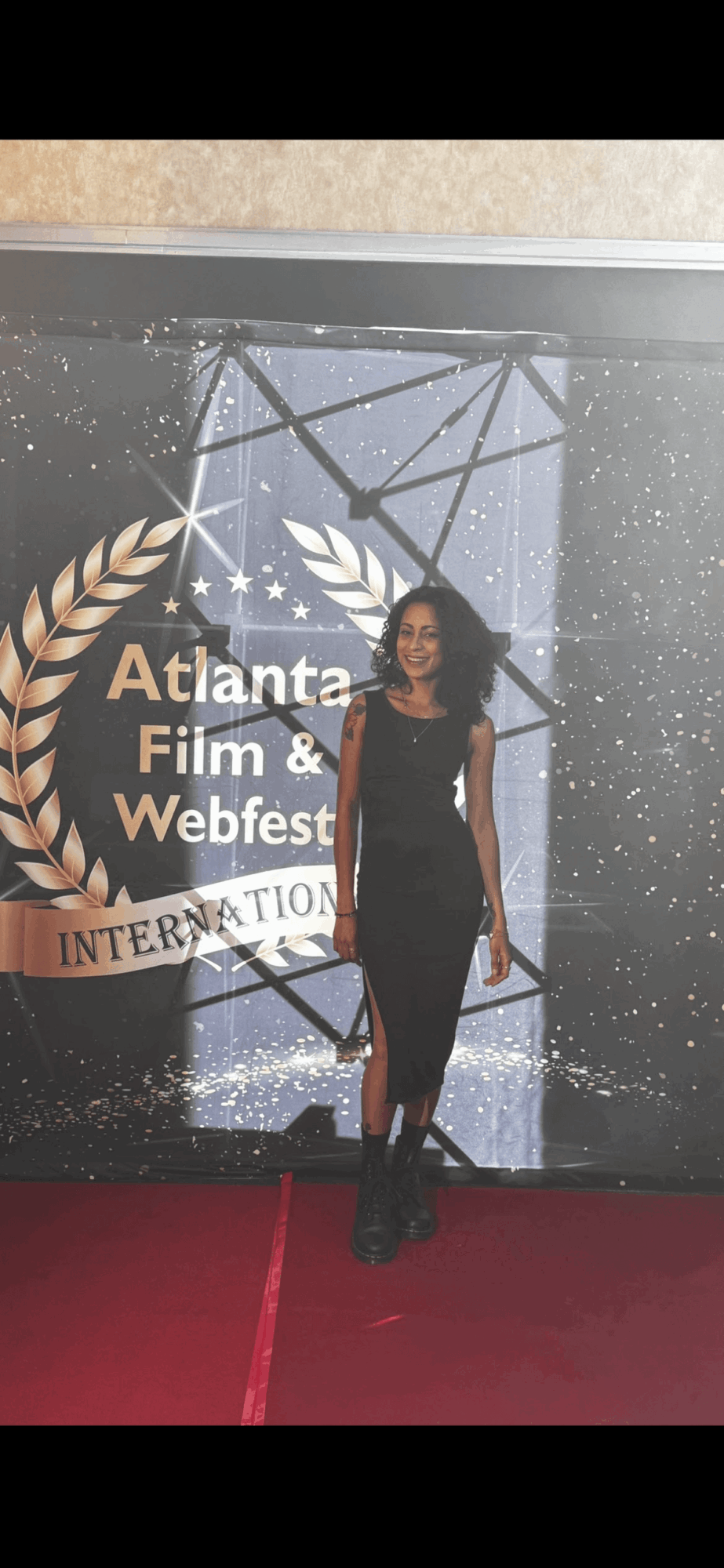 Woman in black dress standing on red carpet in front of Atlanta Film & Webfest backdrop.
