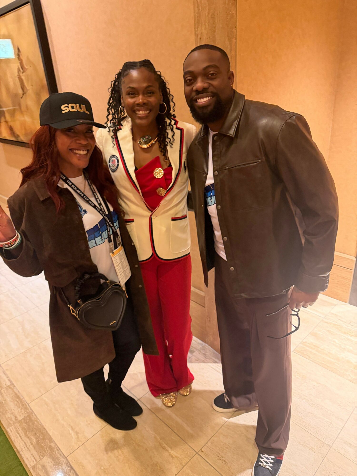 Three people standing indoors, two women and one man, smiling and posing for a photo.