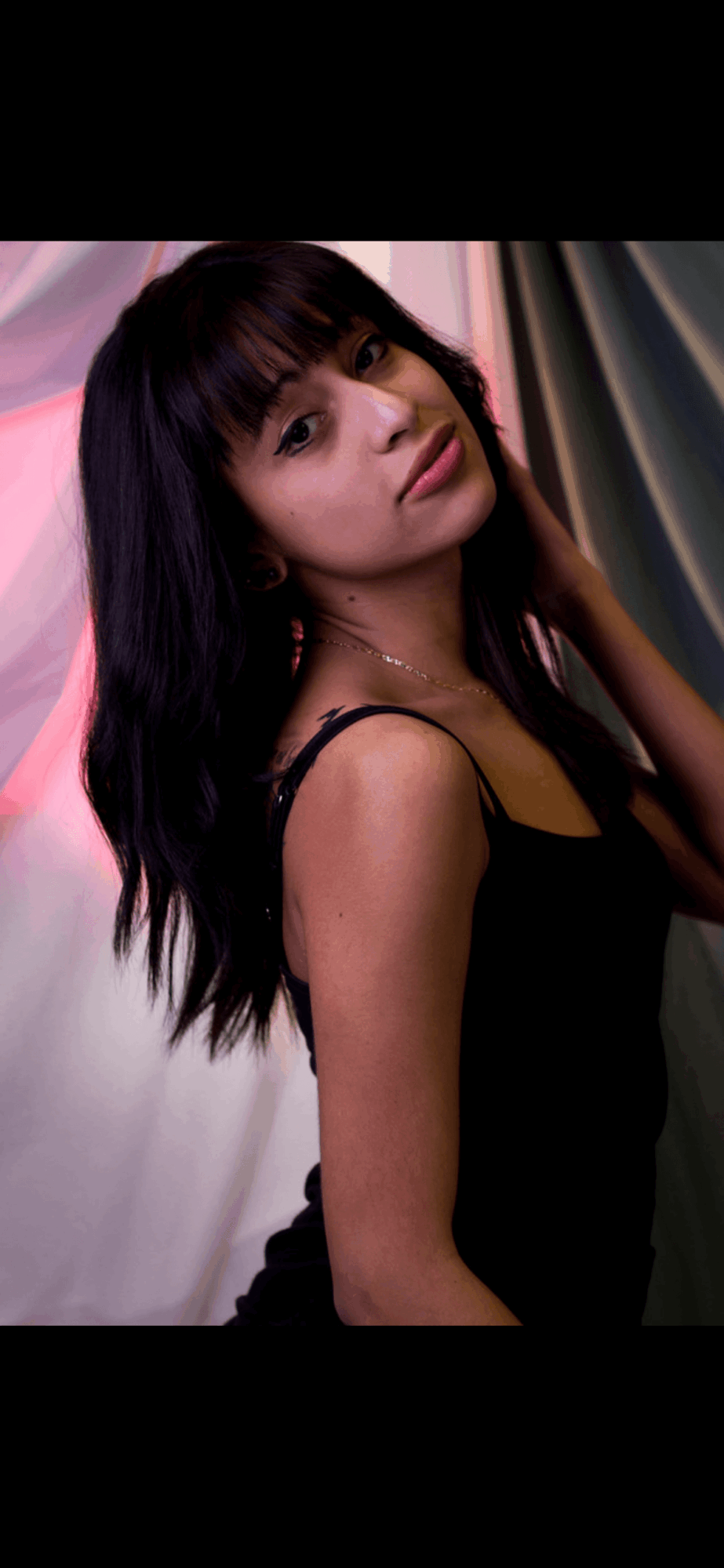Young woman with dark hair and bangs, wearing a black top, looking at the camera with a slight smile.
