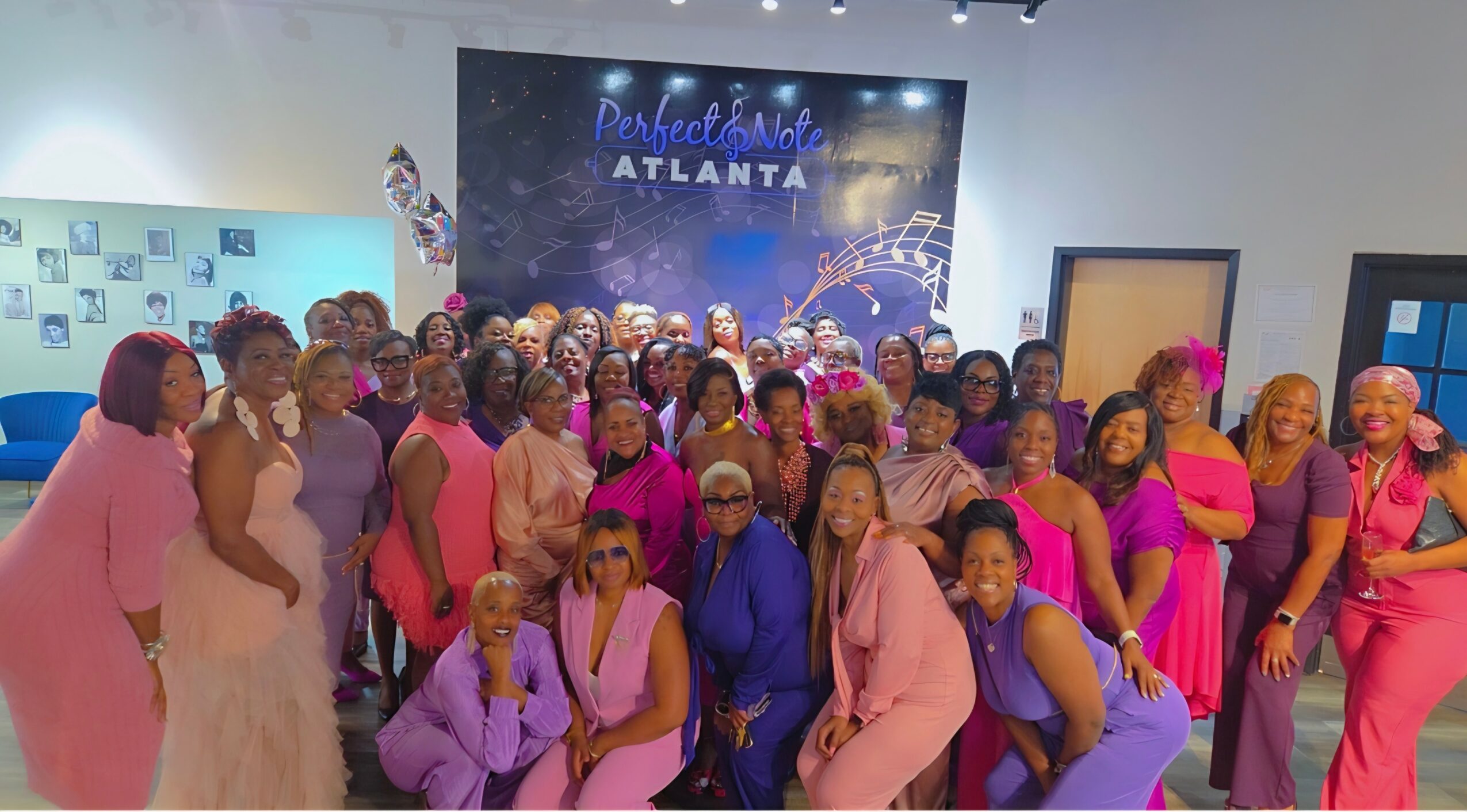 Group of people in colorful clothing posing in front of a stage with a sign that reads 'Celebration ATLANTA'.
