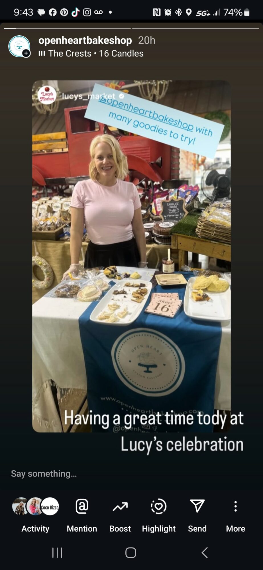 Woman standing behind a table with desserts at Lucy’s celebration, decorated with a blue and white tablecloth, smiling.
