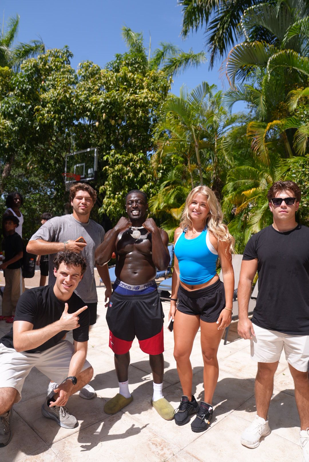Group of people standing outdoors among trees and plants, smiling and posing for a photo.