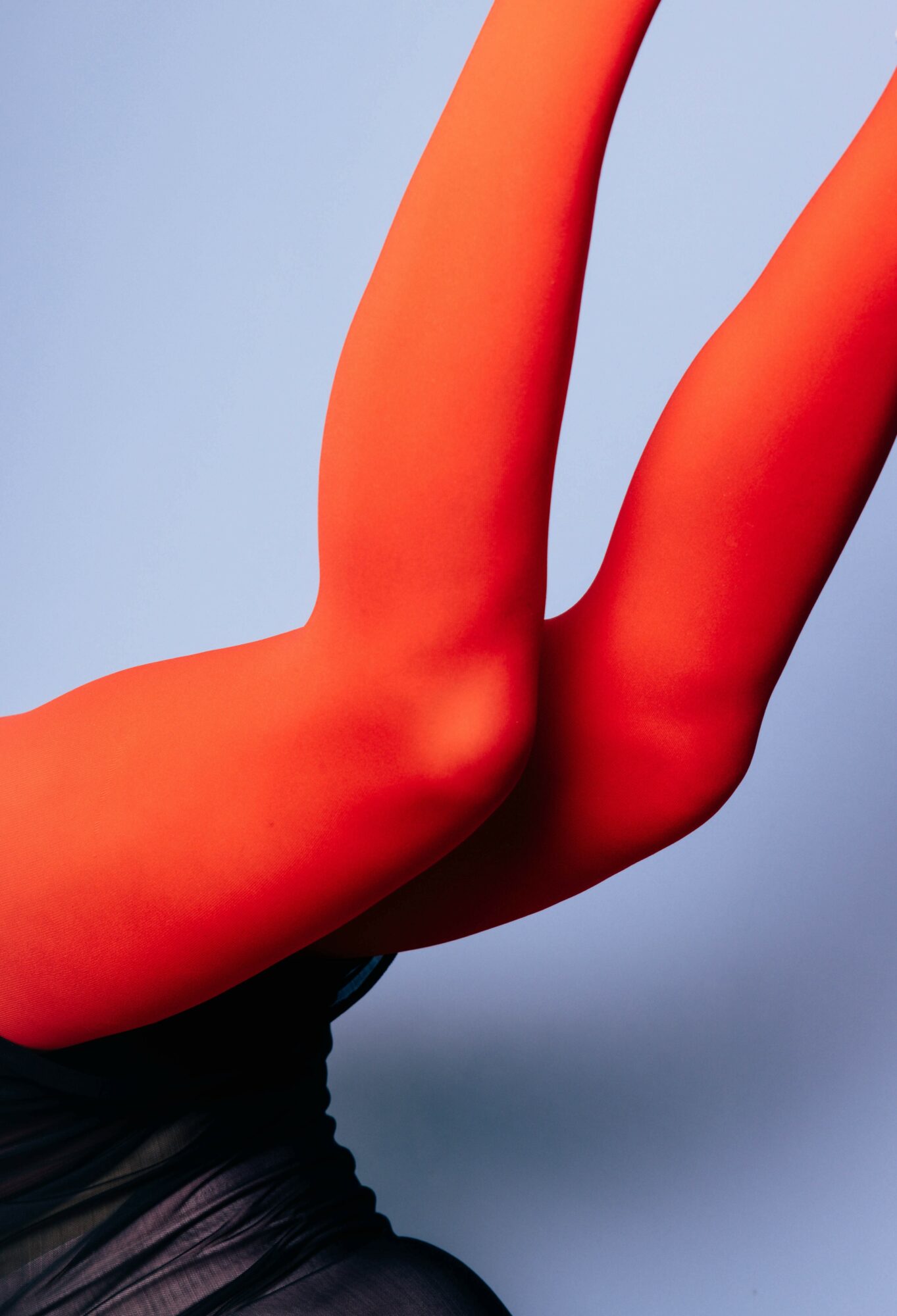Close-up of a person's arm and hand with bright orange skin against a light blue background.