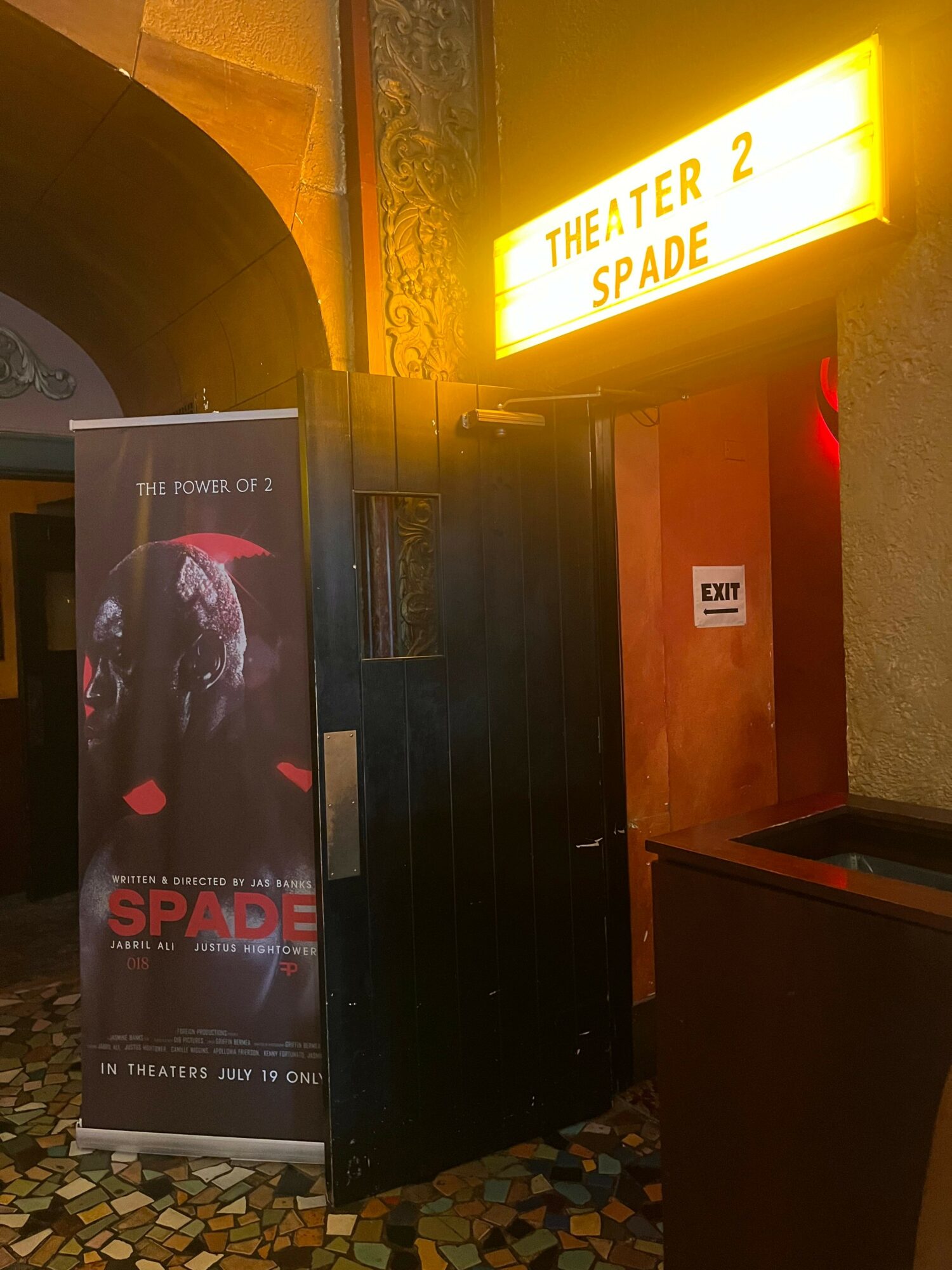 Elevator door with a sign above reading 'ENTER 2nd SPARE' and a promotional banner for a movie or event.
