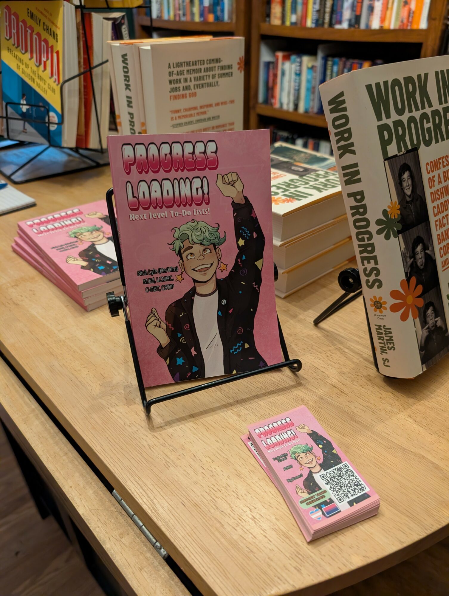 Display stand with a pink book titled 'Fearless Loading' featuring a woman with glasses and curly hair, in a bookstore.