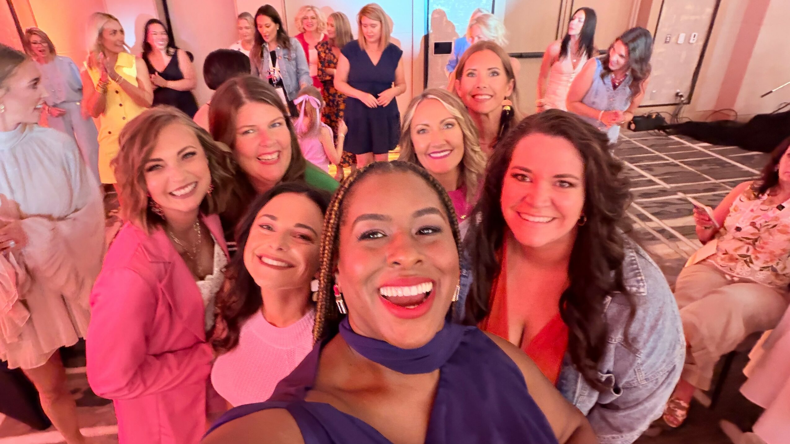 Group of women smiling and posing together indoors at a social event.