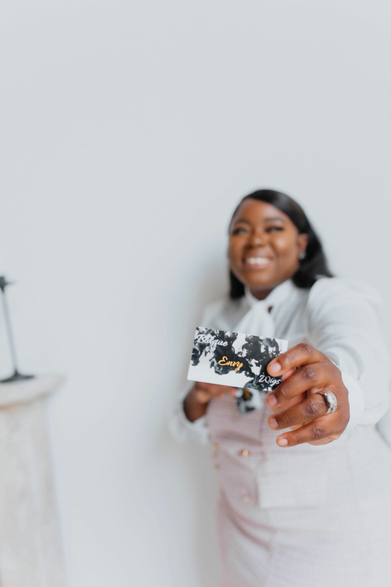 Person smiling and holding a card towards the camera, with a plain light background.