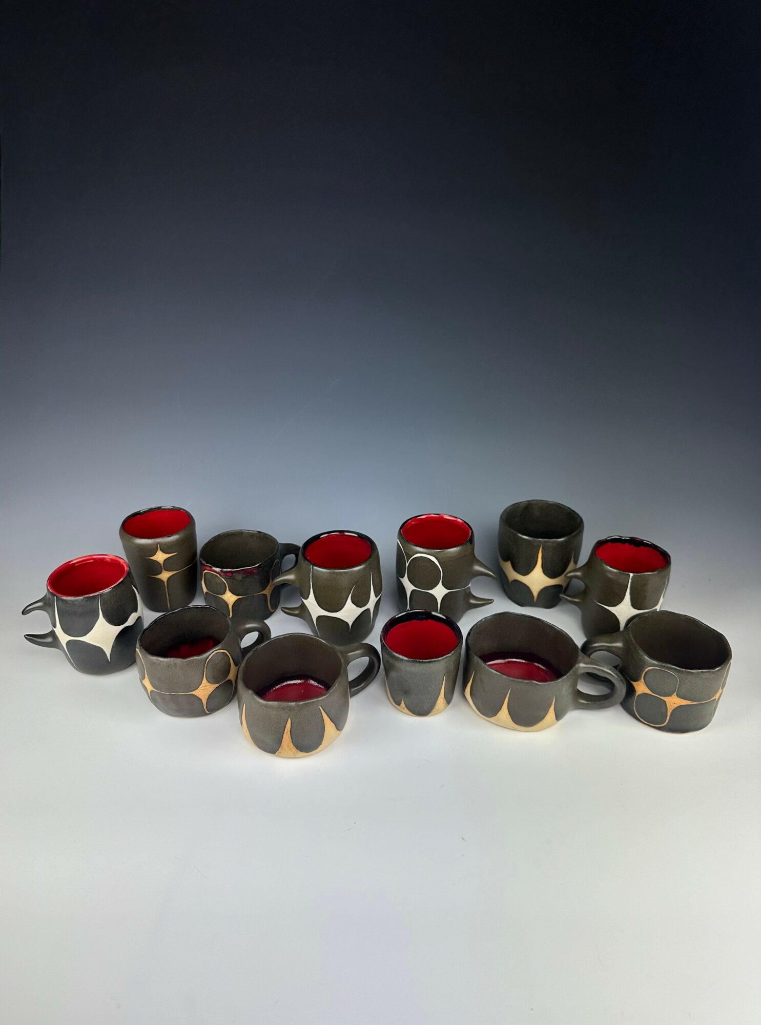 Group of black and red cups with star patterns arranged on a surface, with a gradient background.