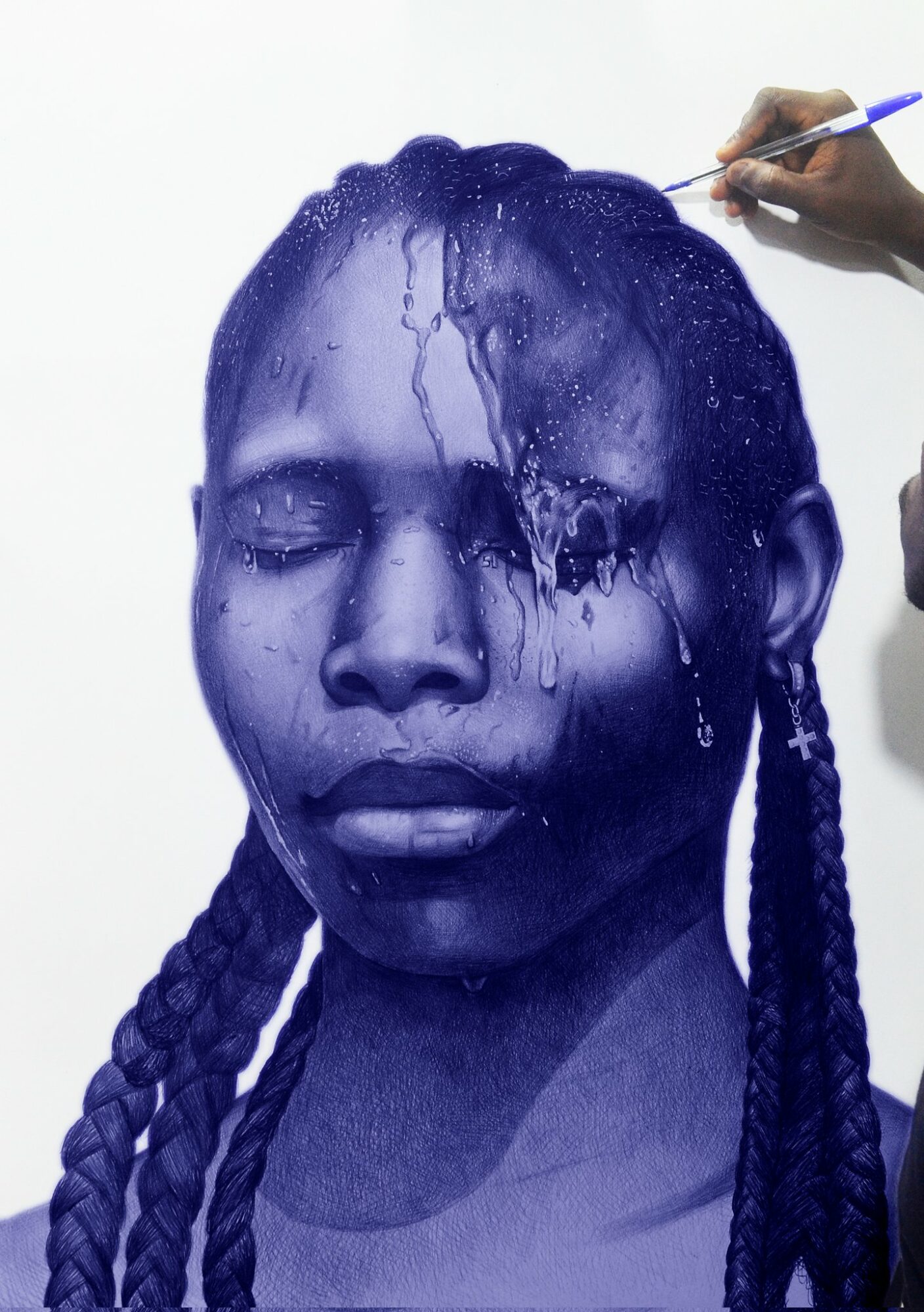 Person's face painted blue with water being poured over it, hair styled in braids, hand holding a brush or tool, white background.