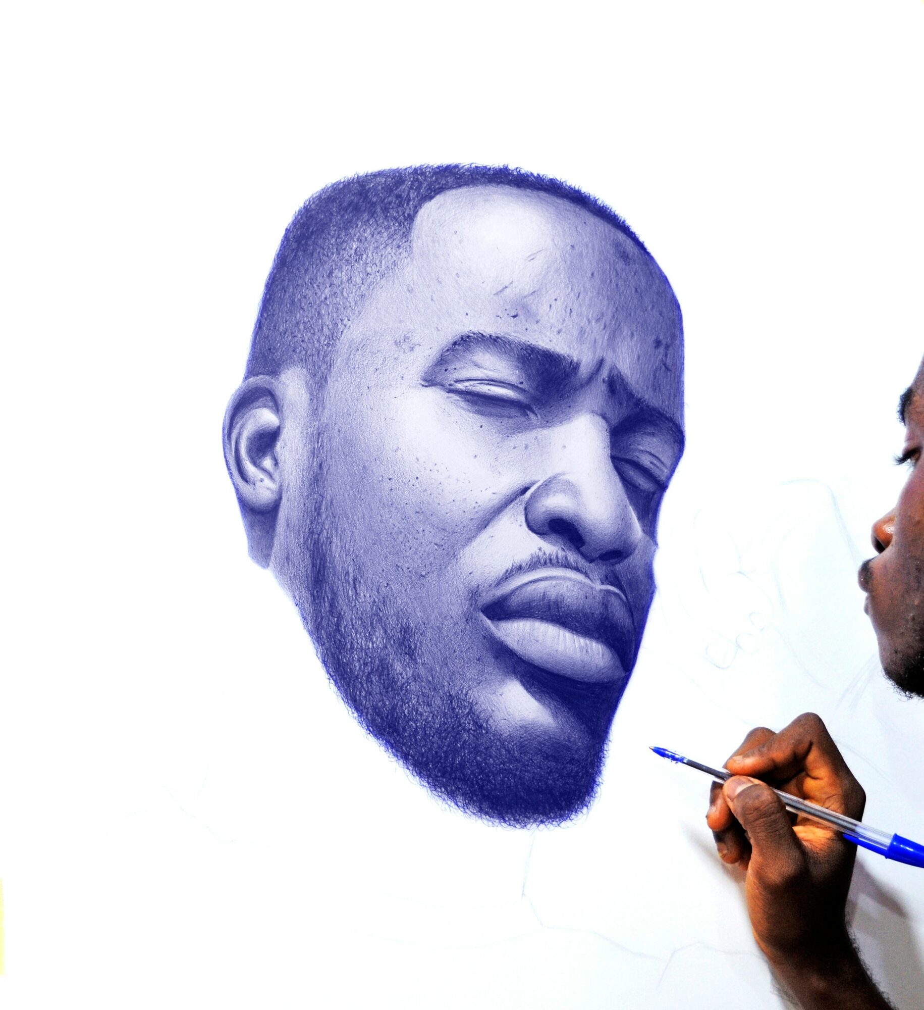 Artist painting a realistic portrait of a man's face on paper, focusing on facial features and expression.