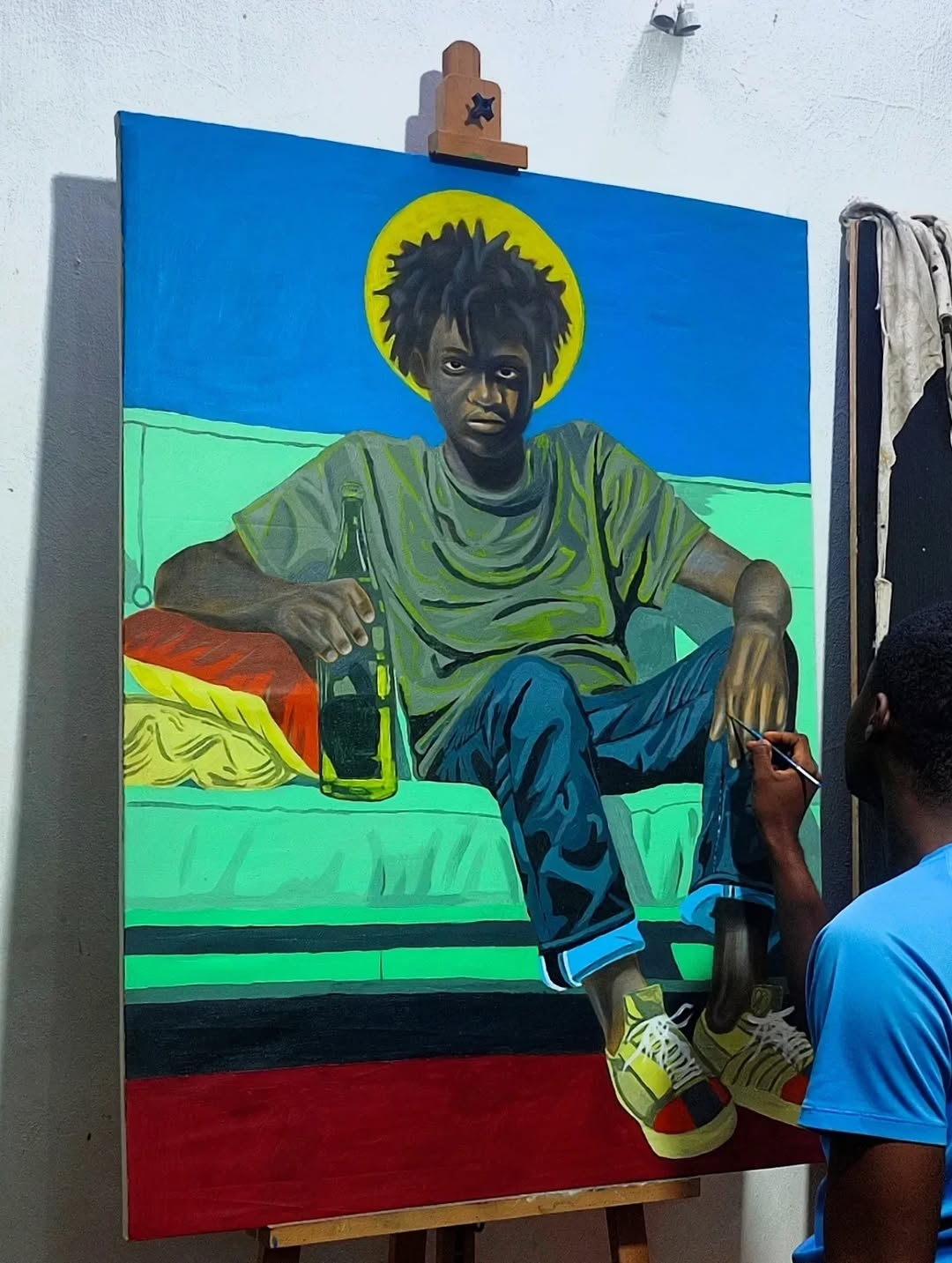 Person painting a colorful portrait of a young man with an afro, sitting on a bed with a drink, in a vibrant style.