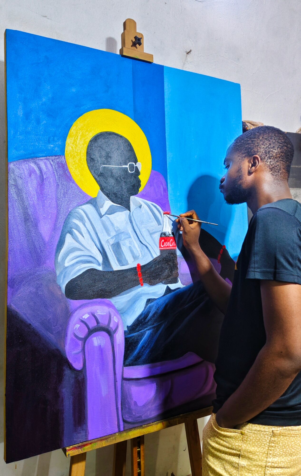 Young man painting a portrait of a seated person with a yellow halo, purple armchair, and blue background.