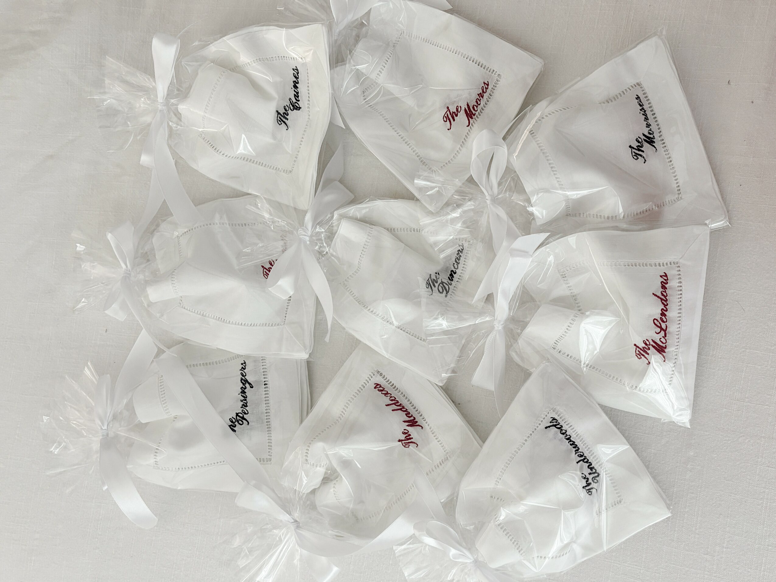 Multiple white wrapped candies with handwritten labels in clear plastic wrappers, scattered on a white surface.