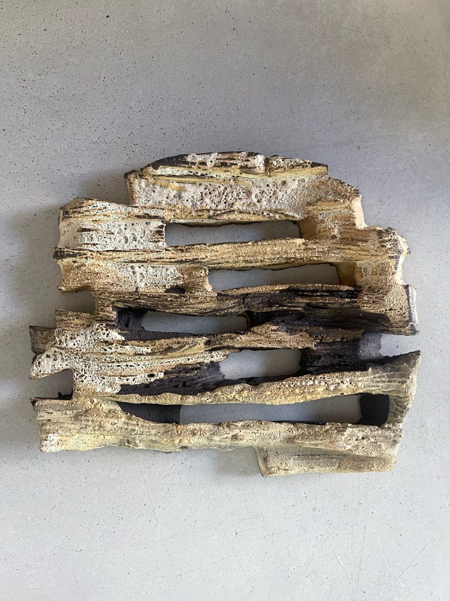 Stacked pieces of weathered wood with gaps, placed on a light surface.