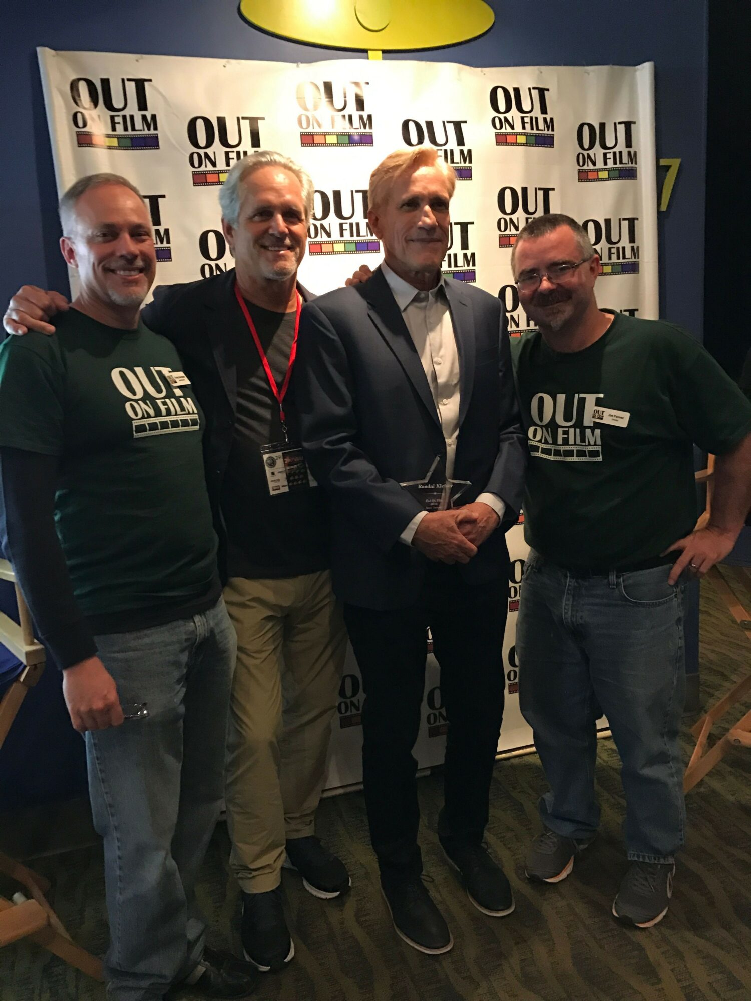 Four men standing together in front of a backdrop with text, smiling and posing for a photo.