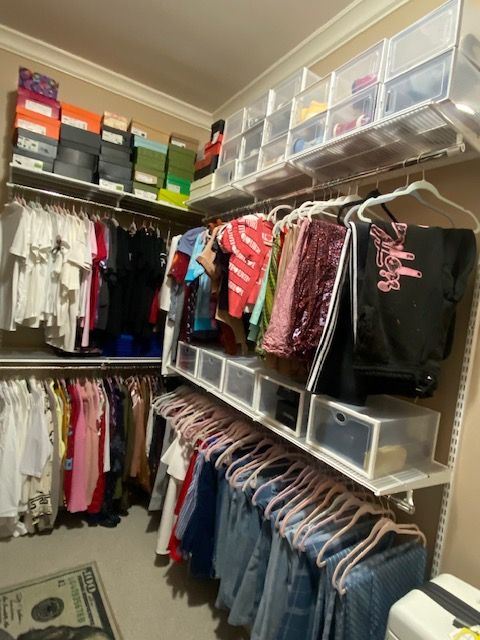 Closet shelf with organized fabric, paper, and storage boxes, and a dollar bill visible at the bottom right.