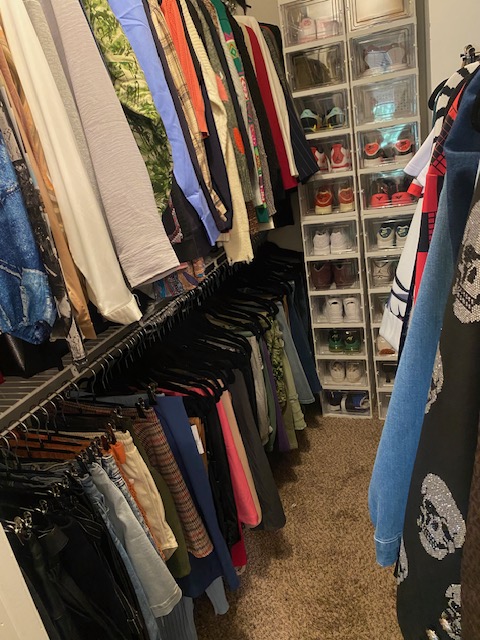 Clothing racks with hanging pants and shirts in a store, shelves with organized boxes in the background.