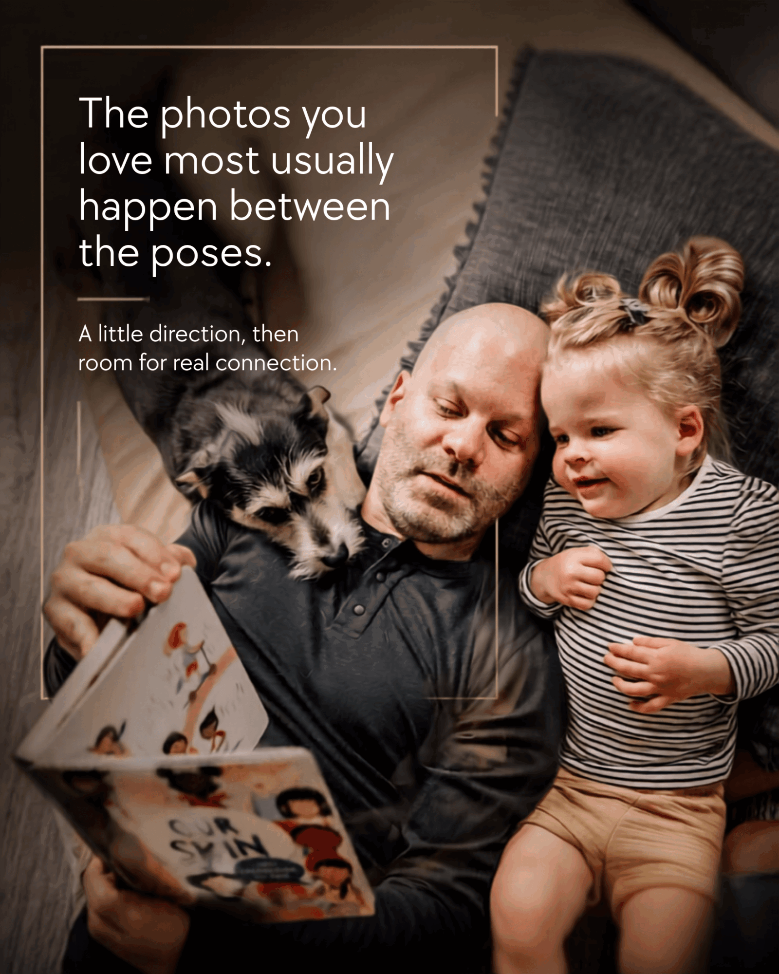 A man, a young girl, and a puppy look at a photo album together on a couch.