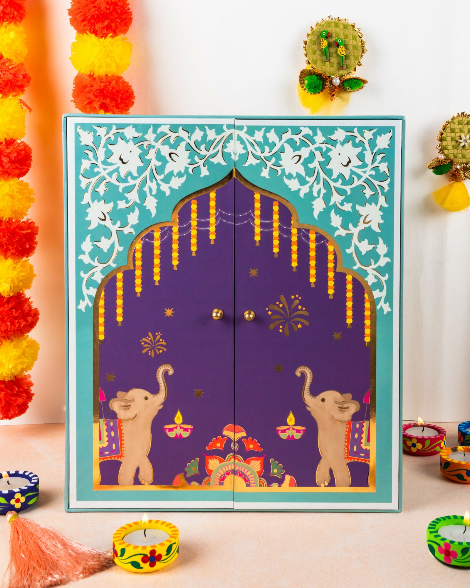 Decorative door with elephants, floral patterns, and hanging ornaments, celebrating a festive or cultural event, with colorful decorations around it.
