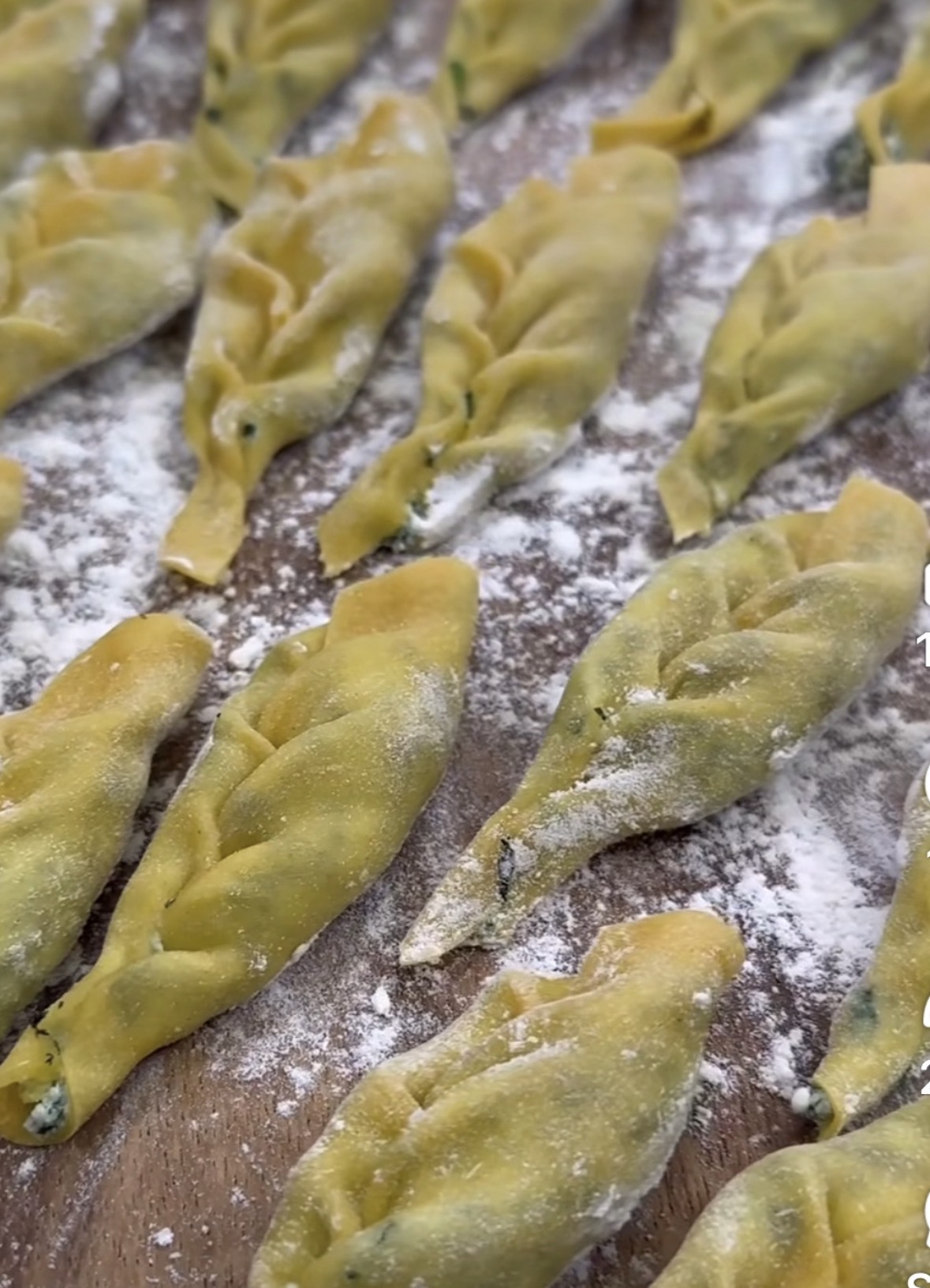 Uncooked tortellini pasta arranged on a floured surface, ready for cooking.