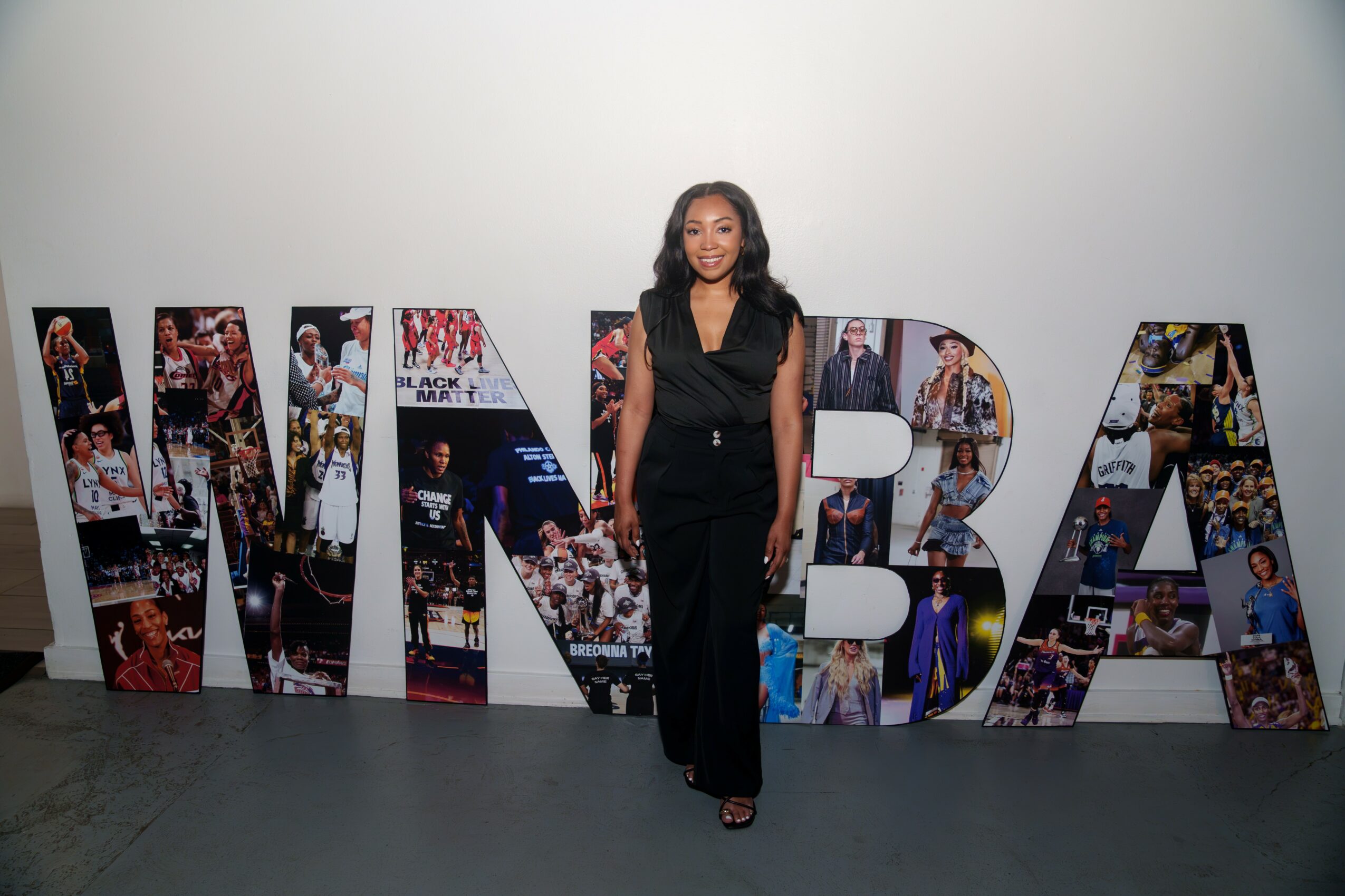 Woman in black dress standing in front of large collage letters spelling 'MNBA' with photos inside the letters.