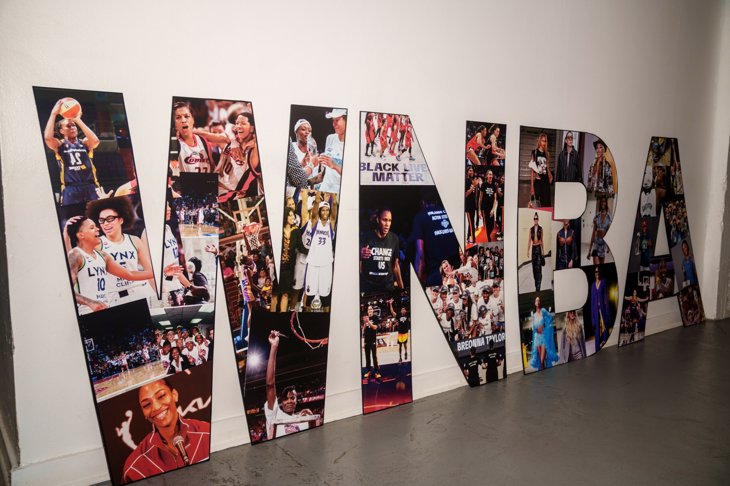 Large three-dimensional letters spelling 'LIMBA' with images of basketball players inside each letter, on a white wall.