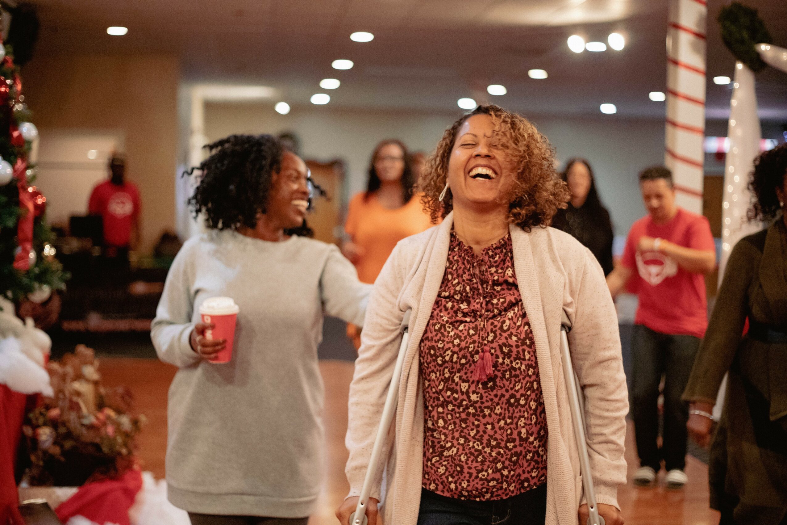 People celebrating at a holiday party, smiling and laughing, with Christmas decorations in the background.