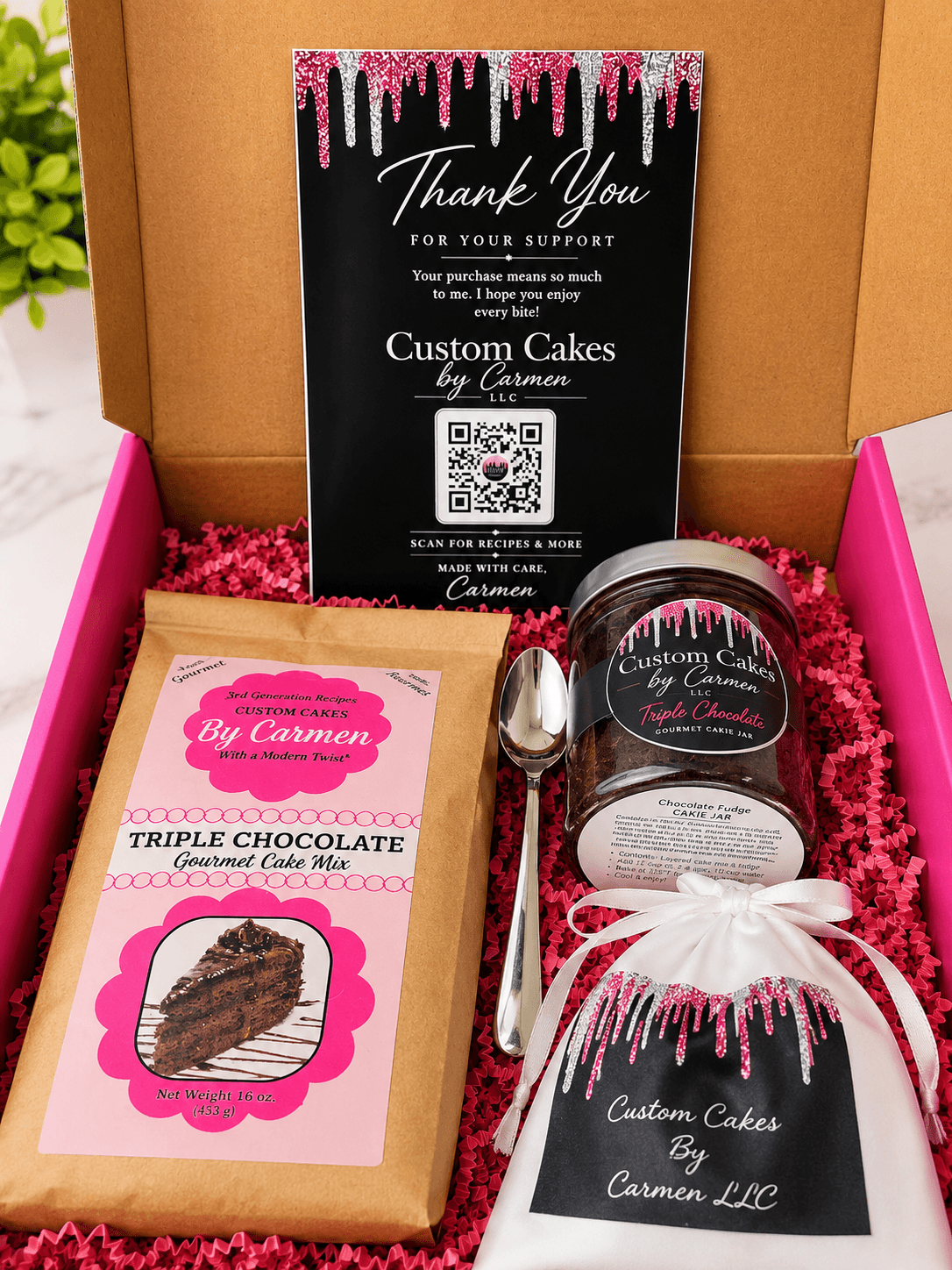 Box with cake, spoon, and thank you card from Custom Cakes by Carmen LLC, decorated with pink and black design, inside a pink box.