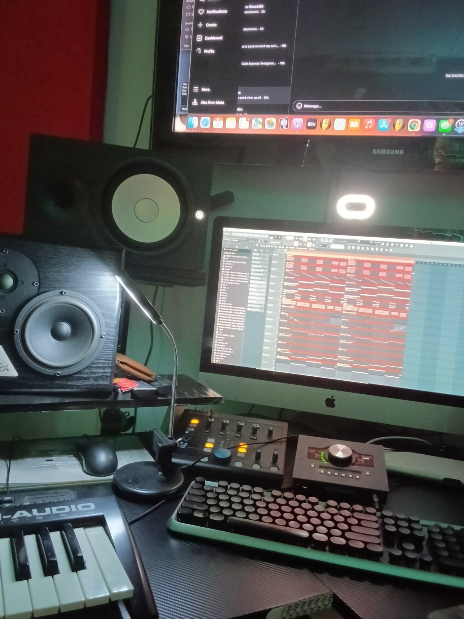 Music production setup with two monitors, speakers, keyboard, and audio equipment on a desk.