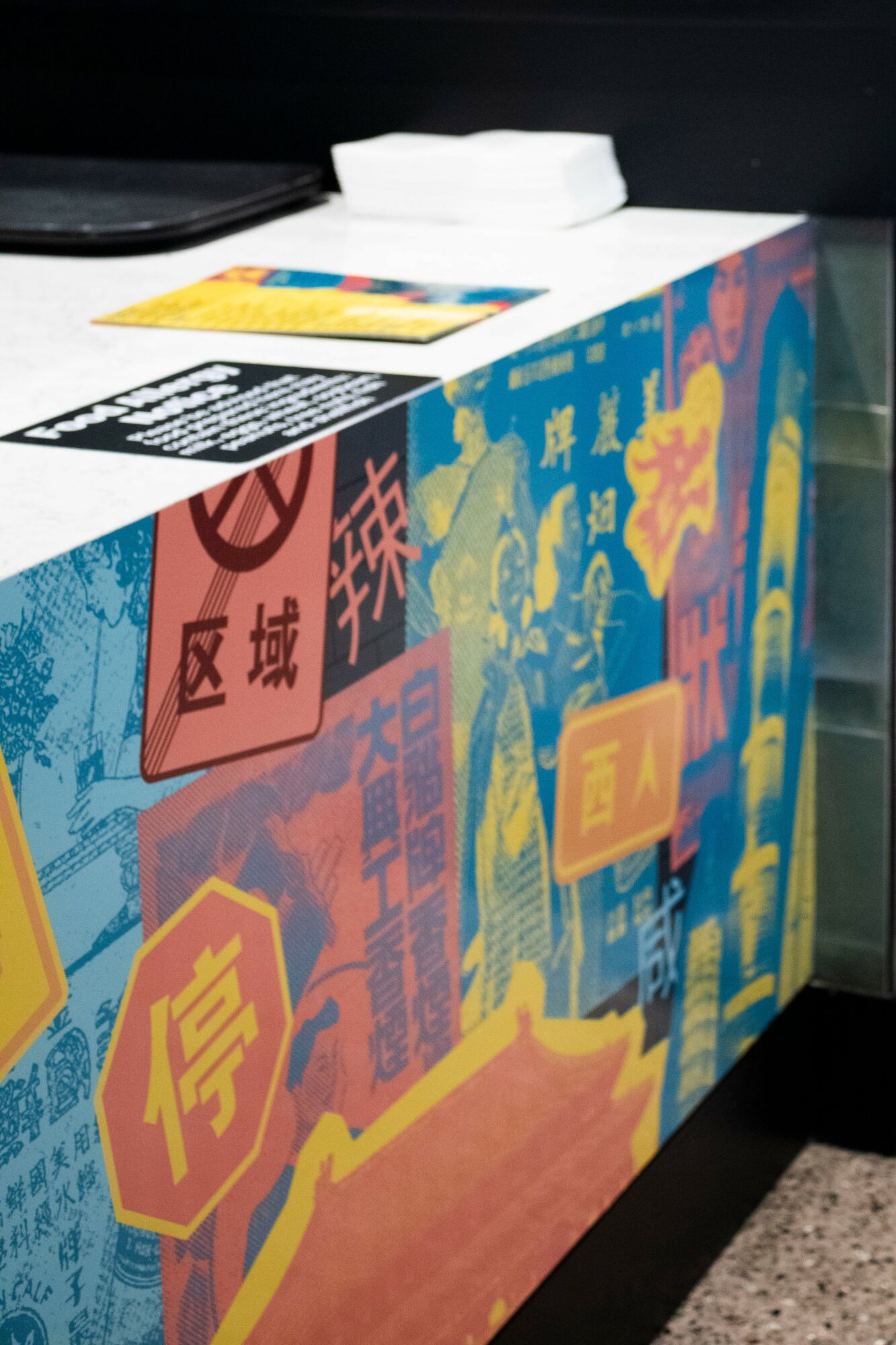 Colorful box with Chinese characters and symbols, placed on a black surface with a white object on top.