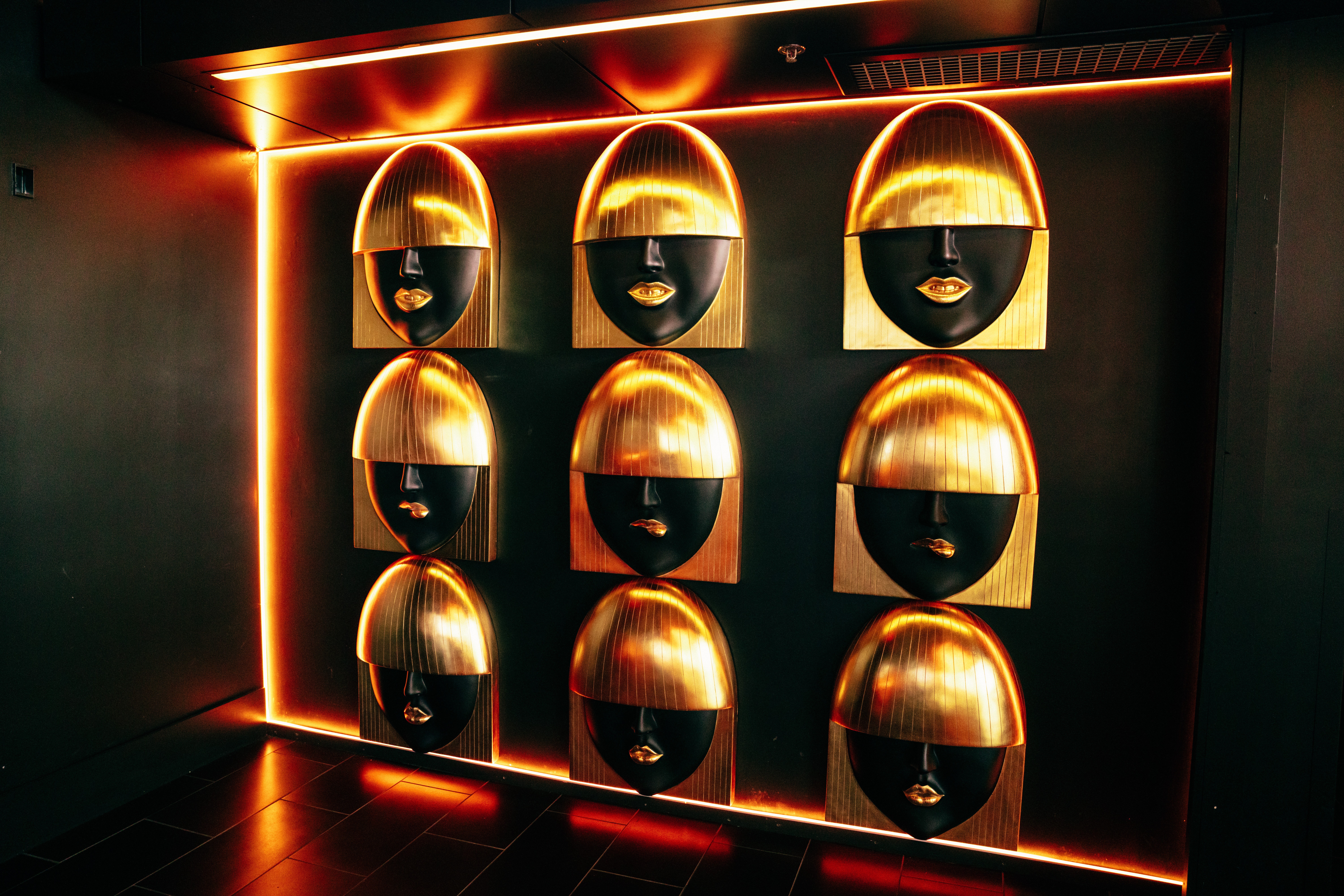 Display of nine black and gold spherical objects arranged in a 3x3 grid with warm lighting and reflective surfaces.