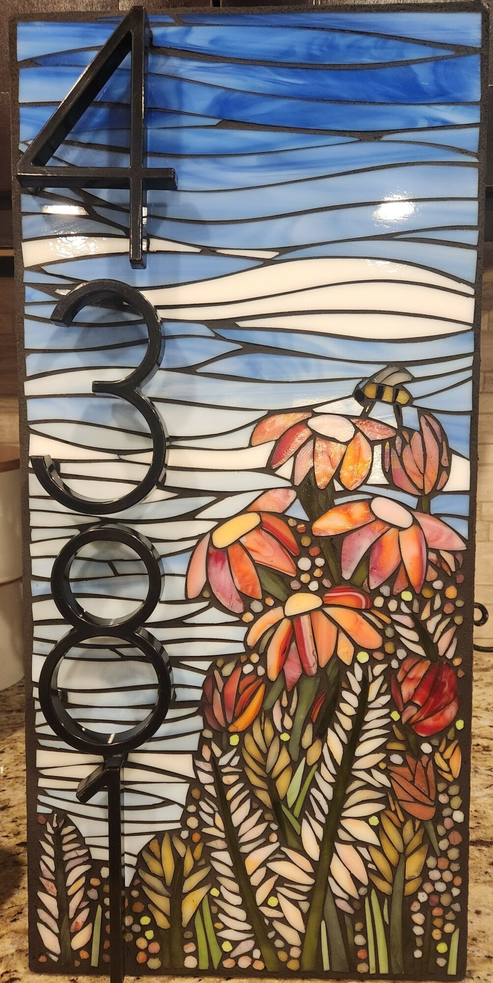 Stained glass window with flowers, sky, and clouds, featuring a large number 3000 on the left side.