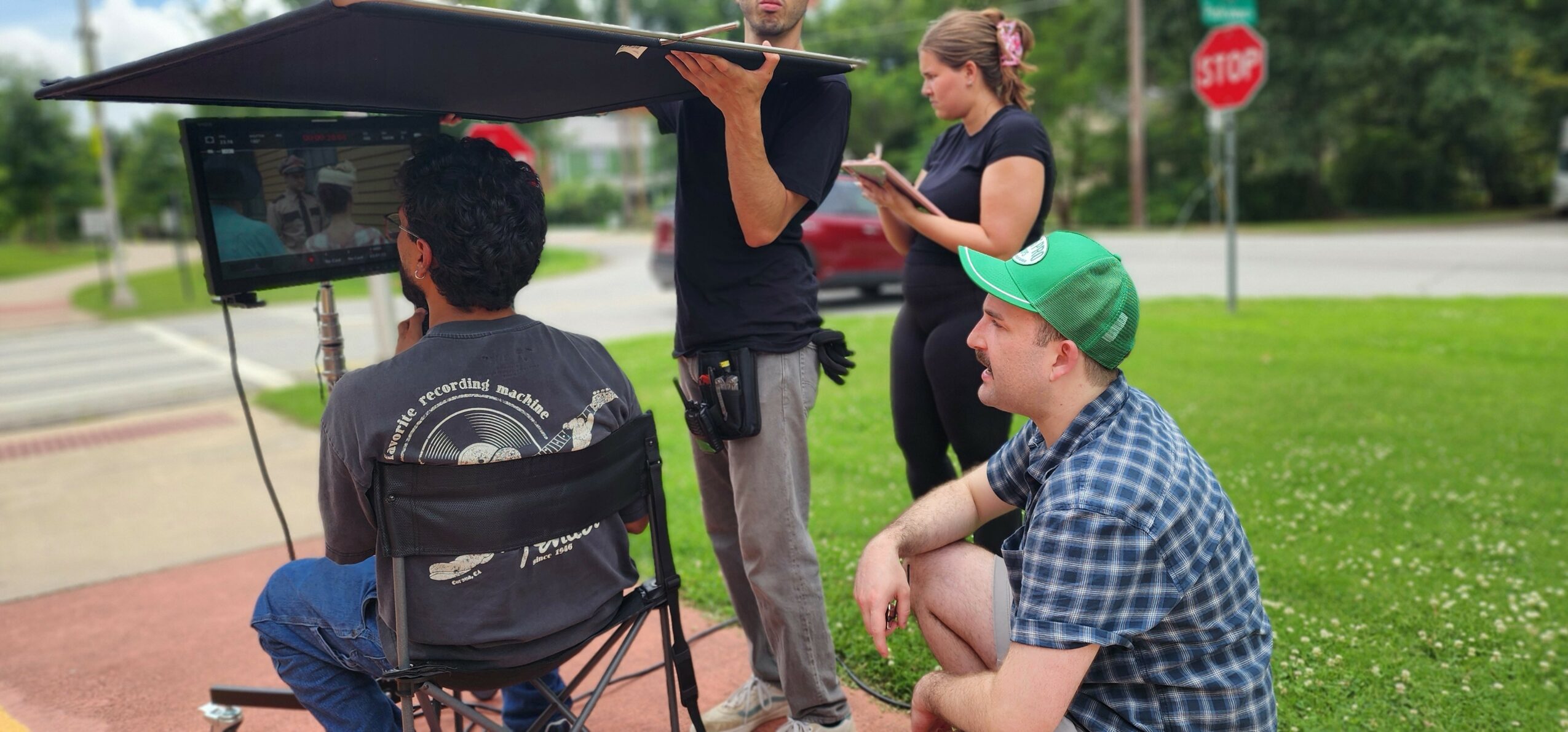 Two women and two men outdoors near a stop sign, with one woman operating a drone and the others watching.